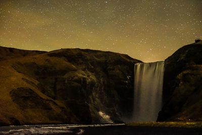 Scenic view of waterfall against sky at night