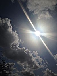 Low angle view of sun shining through clouds