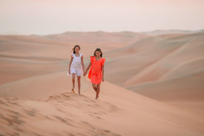 Rear view of people walking on sand dune