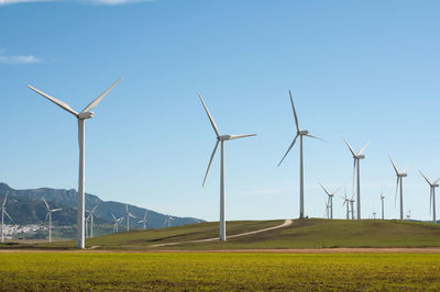 Wind turbines on field against sky