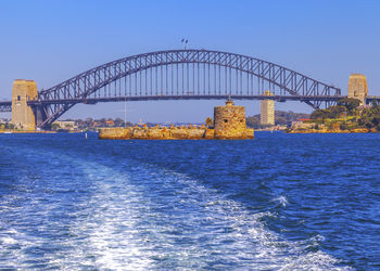 Bridge over sea against blue sky, sydney harbour.