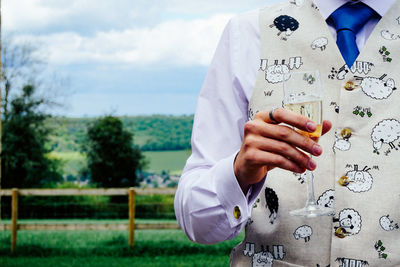 Midsection of man holding champagne flute