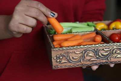 Midsection of woman holding container with various vegetables