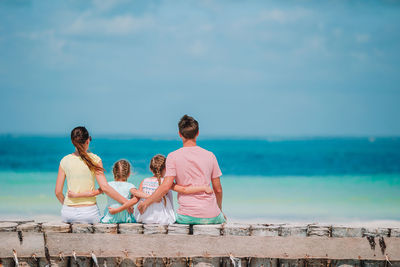 People sitting by sea against sky