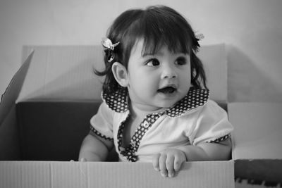 Cute toddler girl relaxing in cardboard box at home