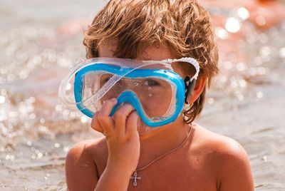 Cute boy looking through the glass of a diving mask