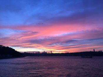 Scenic view of river against dramatic sky during sunset