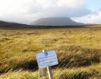 Information sign on field against sky