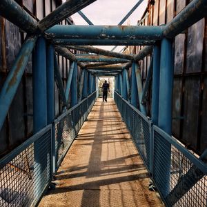 Rear view of woman walking on footbridge