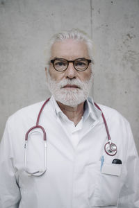 Portrait of a serious doctor at a concrete wall