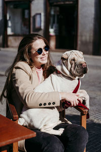 Midsection of woman with dog sitting outdoors