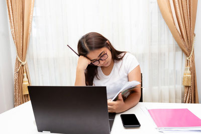 Woman using phone while sitting on table