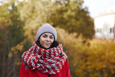 Portrait of young woman standing against trees