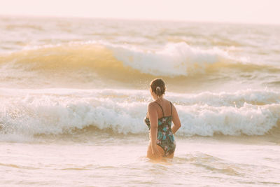 Rear view of woman standing at beach