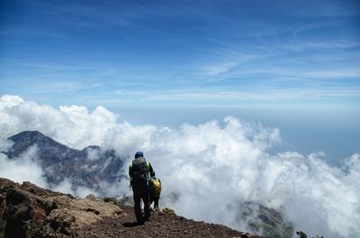 Rear view of men on mountain against sky