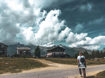 Rear view of man standing amidst buildings against sky