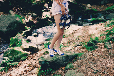 Young hipster girl staying on a rock at river in forest in printed bright socks