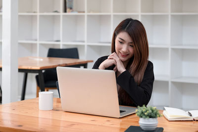 Young woman using phone while sitting on table