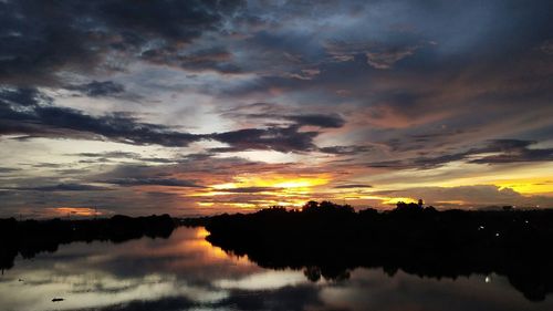 Scenic view of dramatic sky over silhouette trees during sunset