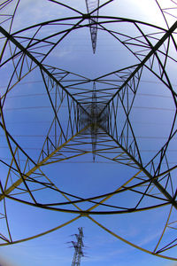 Low angle view of electricity pylon against clear blue sky