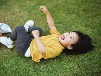 High angle view of boy lying on grassy field