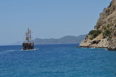 Old ship sailing in sea against clear blue sky