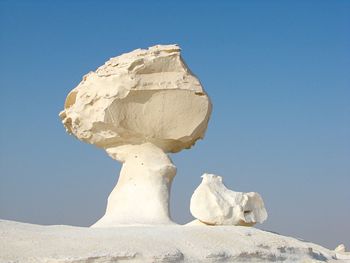 White rock formation in desert against clear blue sky