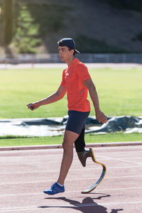 Side view of athlete with prosthetic leg walking on running track