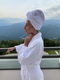 Side view of woman standing on balcony against mountains