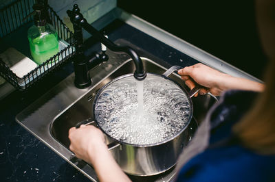 Midsection of woman filling water in bowl in kitchen