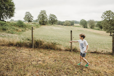 Boy pointing off camera in garden with fields in the background