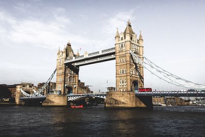 Tower bridge over river in city against sky