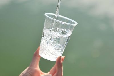 Midsection of woman holding glass of water