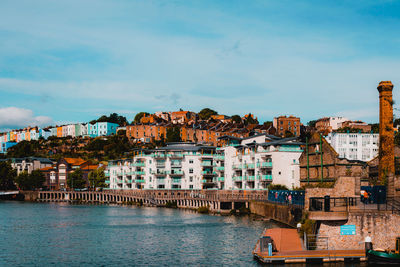 Houses by river in town against sky