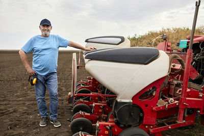 Mature male farmer standing by tractor at farm