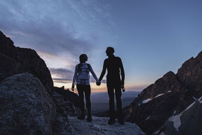 A couple hold hands while hiking in the mountains at dawn, wyoming