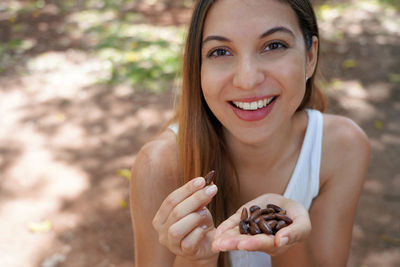 Close-up of healthy woman eating baru seeds in the park. looks at camera.