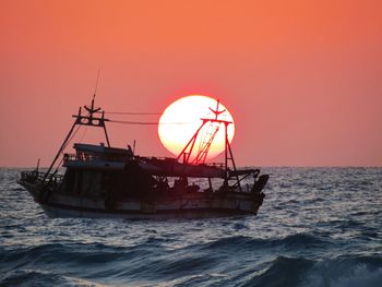 Boat in sea against sky during sunset