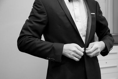 Midsection of businessman adjusting suit
