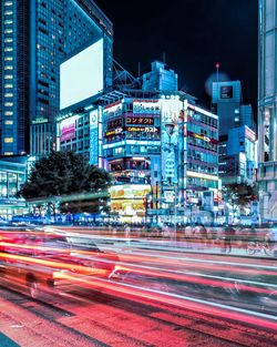 Light trails on city street by buildings at night