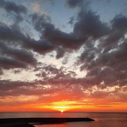 Scenic view of sea against dramatic sky during sunset