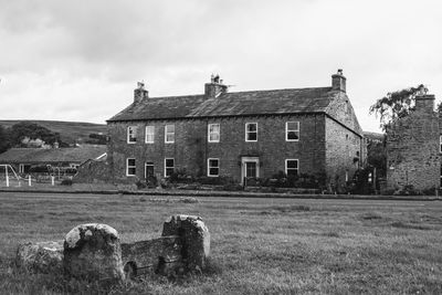 Old building by field against sky