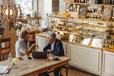 Two businessmen with laptop meeting in a cafe