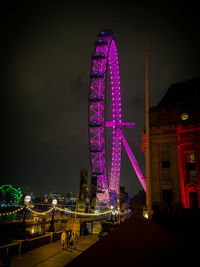 Illuminated ferris wheel in city at night