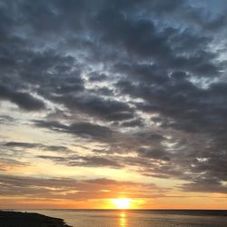 Scenic view of sea against dramatic sky during sunset