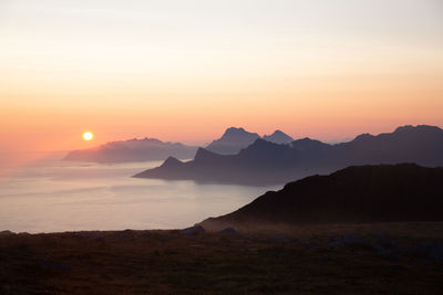 Scenic view of sea and silhouette mountains against sky during sunset