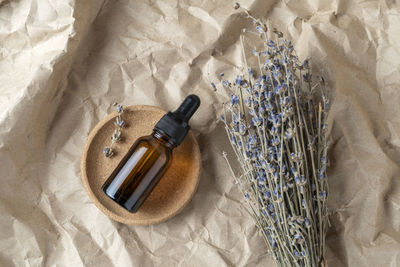 A face serum or oil in a brown dropper bottle standing on a beige table background