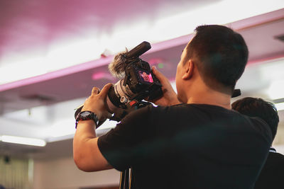 Man photographing through camera against ceiling