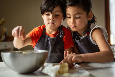 Two girls wearing grey aprons busy cooking