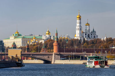 View of buildings by river against sky in city